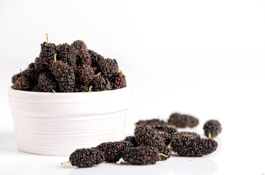 Beyaz arka planda izole edilmiş beyaz seramik kasede taze organik dut meyvesi yakın