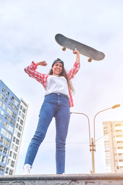 Mooie jonge vrouw winnen zittend op skatepark op de helling met haar longboard. — Stockfoto