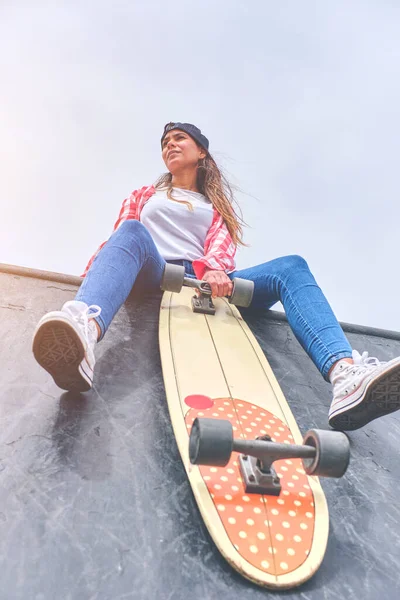 Krásná a módní žena pózuje s skateboard Mladá žena je pózování s skateboard ve městě, žena teenager venkovní s dlouhou palubě. — Stock fotografie