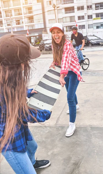 Ragazze arrabbiate che lottano per uno skateboard nello skate park. amici che fanno parodia wrestling. — Foto Stock