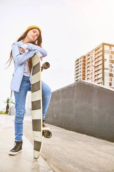 Meisje dat plezier heeft met skateboarden in skate park, Portret van lachende jonge vrouwelijke skateboarder die haar skateboard vasthoudt. Recreatief activiteitsconcept. — Stockfoto