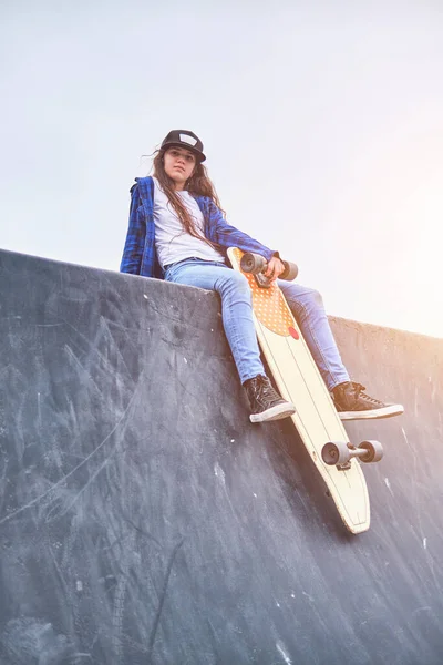 Meisje dat plezier heeft met skateboarden in skate park, Portret van lachende jonge vrouwelijke skateboarder die haar skateboard vasthoudt. Recreatief activiteitsconcept. — Stockfoto