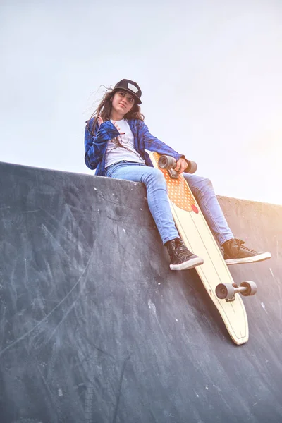 Meisje dat plezier heeft met skateboarden in skate park, Portret van lachende jonge vrouwelijke skateboarder die haar skateboard vasthoudt. Recreatief activiteitsconcept. — Stockfoto