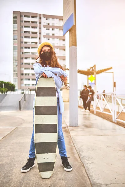 Ragazza che si diverte a cavalcare skateboard allo skate park, Ritratto di sorridere giovane skateboarder femminile tenendo il suo skateboard. Concetto di attività ricreativa. — Foto Stock