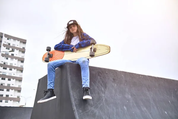 Ragazza che si diverte a cavalcare skateboard allo skate park, Ritratto di sorridere giovane skateboarder femminile tenendo il suo skateboard. Concetto di attività ricreativa. — Foto Stock