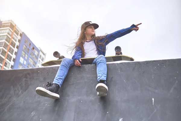 Девушка веселится катаясь на скейтбордах в скейт-парке, портрет улыбающейся молодой женщины-скейтбордистки, держащей свой скейтборд. Концепция рекреационной деятельности. — стоковое фото