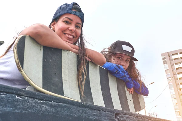 Attraenti amiche che si divertono a cavalcare skateboard allo skate park, Ritratto sorridente di giovani skateboarder che tengono il suo skateboard. — Foto Stock