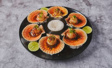 Siyah tabakta yanan kabukları olan deniz tarakları. Lüks restoran yemekleri. Deniz ürünleri, seçici odaklanma.