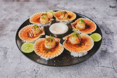 Siyah tabakta yanan kabukları olan deniz tarakları. Lüks restoran yemekleri. Deniz ürünleri, seçici odaklanma.