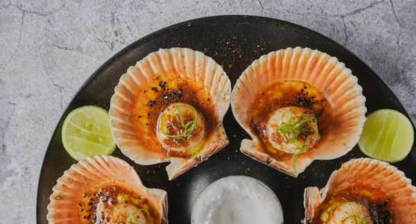 Vieiras con conchas flameadas en un plato negro. Comida de restaurante de lujo. Mariscos, enfoque selectivo. — Foto de Stock