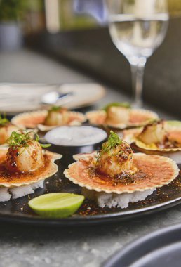 Siyah tabakta yanan kabukları olan deniz tarakları. Lüks restoran yemekleri. Deniz ürünleri, seçici odaklanma.