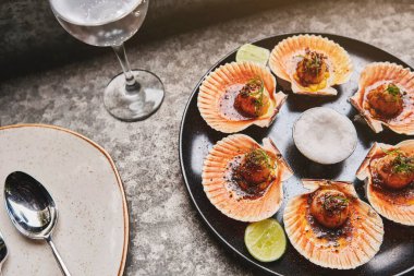 Siyah tabakta yanan kabukları olan deniz tarakları. Lüks restoran yemekleri. Deniz ürünleri, seçici odaklanma.