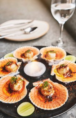 Siyah tabakta yanan kabukları olan deniz tarakları. Lüks restoran yemekleri. Deniz ürünleri, seçici odaklanma.