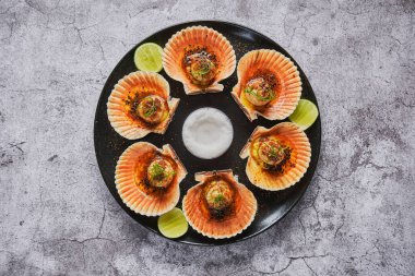 Siyah tabakta yanan kabukları olan deniz tarakları. Lüks restoran yemekleri. Deniz ürünleri, seçici odaklanma.