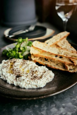 İtalyan peynirli stracciatella -bufalo mozzarella- taze roka ve kızarmış ekmekle servis edilen siyah tabakta. Şefin sunumu.
