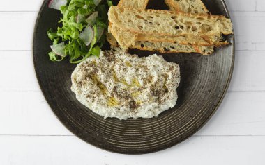İtalyan peynirli stracciatella -bufalo mozzarella- taze roka ve kızarmış ekmekle servis edilen siyah tabakta. Şefin sunumu.