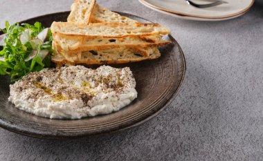 İtalyan peynirli stracciatella -bufalo mozzarella- taze roka ve kızarmış ekmekle servis edilen siyah tabakta. Şefin sunumu.