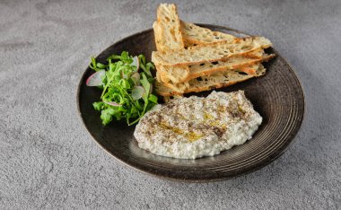 İtalyan peynirli stracciatella -bufalo mozzarella- taze roka ve kızarmış ekmekle servis edilen siyah tabakta. Şefin sunumu.