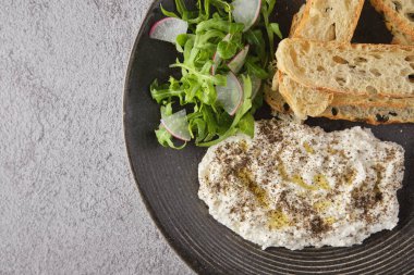 İtalyan peynirli stracciatella -bufalo mozzarella- taze roka ve kızarmış ekmekle servis edilen siyah tabakta. Şefin sunumu.