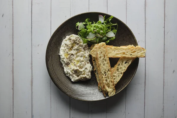 İtalyan peynirli stracciatella -bufalo mozzarella- taze roka ve kızarmış ekmekle servis edilen siyah tabakta. Şefin sunumu.