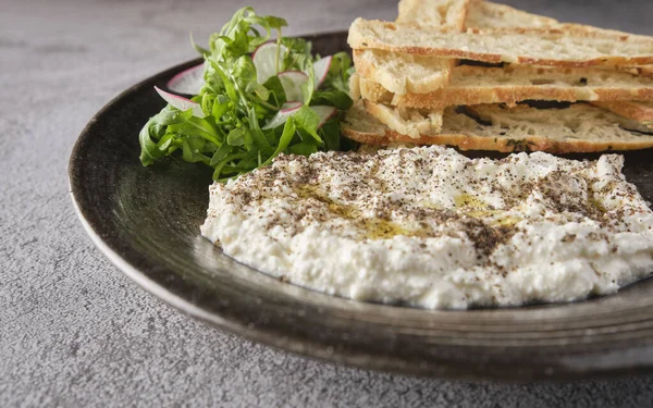 İtalyan peynirli stracciatella -bufalo mozzarella- taze roka ve kızarmış ekmekle servis edilen siyah tabakta. Şefin sunumu.