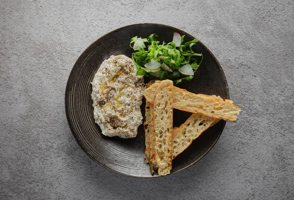 İtalyan peynirli stracciatella -bufalo mozzarella- taze roka ve kızarmış ekmekle servis edilen siyah tabakta. Şefin sunumu.