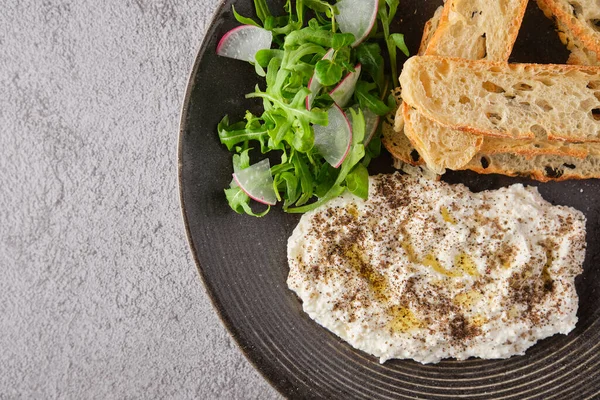 İtalyan peynirli stracciatella -bufalo mozzarella- taze roka ve kızarmış ekmekle servis edilen siyah tabakta. Şefin sunumu.