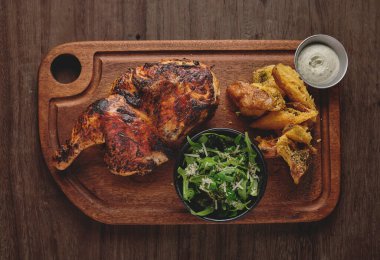 Peru yemeği, Pollo a la brasa veya kızarmış sarı patatesli yarım tavuk ve roka salatası, ahşap tahta. Seçici odak