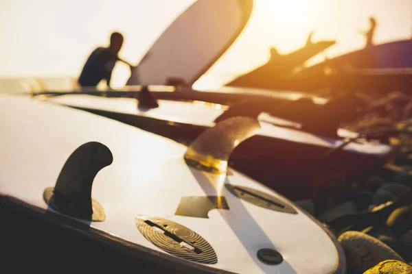 Silueta de una tabla de surf en la playa. Retroiluminación durante el atardecer con cielo dramático y reflexión. Enfoque selectivo — Foto de Stock