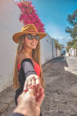 Closeup Young woman holding man hand while leading him on the old street of Arequipa, Peru.