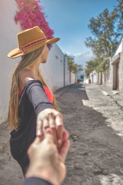 Closeup Young woman holding man hand while leading him on the old street of Arequipa, Peru.