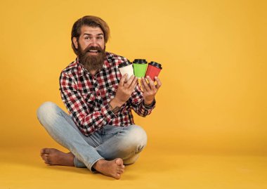 Kafe reklamı. Kahve molası veriyor. Yakışıklı, olgun bir adam içki içiyor. Bir fincan kahve ya da çay al. Yaşam tarzı konsepti. Bir fincan kahveli hippi adam. Kopyalama alanı