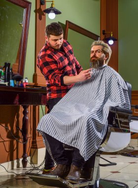 Sakal bakımı. Berber dükkanında olgun bir adam. Kuafördeki vahşi sakallı adam. Erkek müşterisi olan profesyonel berber. Sakallı ve bıyıklı hippi. Adam yeni saç stili istiyor. Erkek güzelliği ve moda