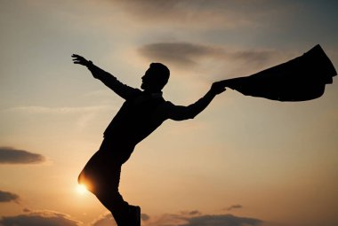 Güneşin doğuşunda özgürce dans eden bir adamın silüeti.