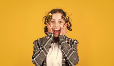 Göz bantlı mutlu çocuk. Saçlarının etrafında kıvırcık kızlar. Güzel bir saç stili yap. Kuaför salonu. Sarı arka planda saç tokası ve saç tokası olan bir kız. Harika bir saç stili.