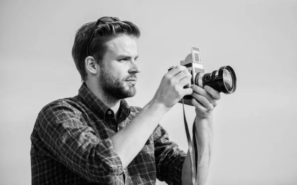 Verslaggever maakt foto 's. Vintage apparatuur. Blogger schiet vlog. Vakantie tijd. Knappe blogger jongen retro camera. Kerel buiten blauwe lucht achtergrond. Fotojournalist concept. Reisblogger — Stockfoto