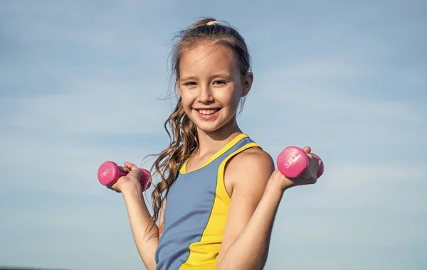 Szczęśliwy nastolatek dziewczyna nosić odzież sportową do treningu ze sztangi na tle nieba, trening fizyczny — Zdjęcie stockowe