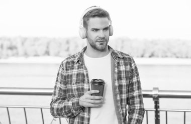 Ne güzel bir sabah. Rahatlama zamanı. yeni dijital teknoloji. Sabah taze kahveyle başlar. Kulaklıklı yakışıklı genç adam. Modern hayat. Müzik dinle. Adam sıradan tarzda içki içer, kahve içer.