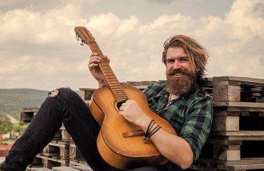 Uzun saçlı hippi ve bıyıklı gitarist. Müzik aleti olan erkek gitarist. Country müzik konsepti. Sakallı adam akustik gitar çalar. Adam insani duygularını ifade ediyor. # Kendini bırak havaya #