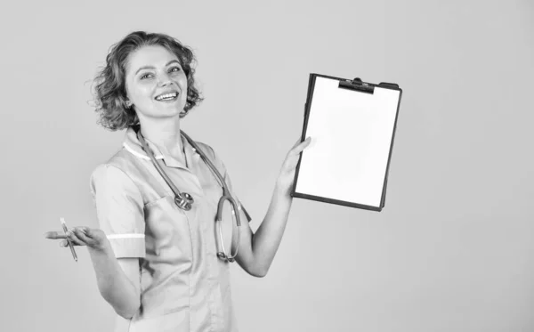 Твоя історія медицини в порядку. Портрет милої медсестри з папкою. Вона носить стетоскоп. медсестра тримає зв'язувач і носить стетоскоп. Усміхнена жінка-лікар з текою в однорідному положенні — стокове фото