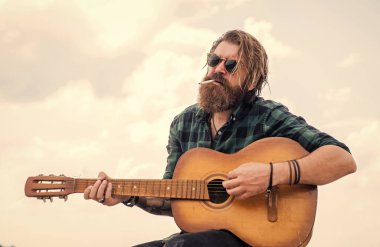 Sigara içiyorum. Sıradan bir erkek gitarist. Müzik ve vokal konsepti. Akustik gitar çalan bir adam. Bıyıklı ve sakallı vahşi adam gitar tutuyor. Müzik dükkanı. Sakallı adam rock yıldızı..