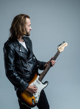 Deri ceketle elektro gitar çalan sakallı rock müzisyeni.