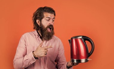 Şuna bak. Oda servisinde kullanışlı. Olgun karizmatik erkek elektrikli su ısıtıcısı kullanır. Sakallı ve bıyıklı adam çay yapıyor. Sıcak çay iç. Sakallı adam mağaza asistanı mutfak aletlerini sunar.