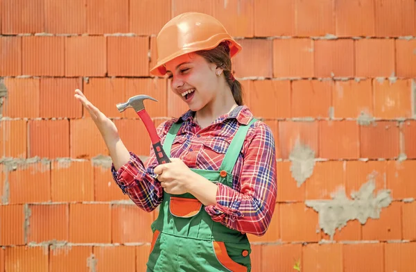 Creatività infantile. Giorno del lavoro all '1 maggio. La ragazzina col cappello duro tiene il martello. miglior riparatore di sempre. imparare a usare il martello. martellante. E 'una brava assistente. Ragazzo ingegnere con martello da lavoro falegname — Foto Stock