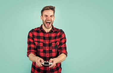 Dijital dünyada yaşamak. Erkek hobisi ve boş zaman. Kareli tişörtlü bir oyuncu. Sakallı adam oyun konsolu kullanıyor. joystick 'li traşsız yakışıklı adam. bilgisayar ve çevrimiçi oyun oyna