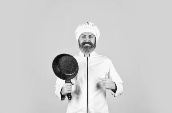 Ustensiles de cuisine antiadhésifs. Friture sans huile. Repas de friture. Une nourriture saine. Ustensiles de cuisine professionnels. Chef barbu préparant le petit déjeuner. Poêle antiadhésive pour la friture. Vases de cuisson émaillés. Man hold pan — Photo