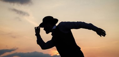 Erkek dansçı silueti şapkasıyla günbatımına karşı dans ediyor.