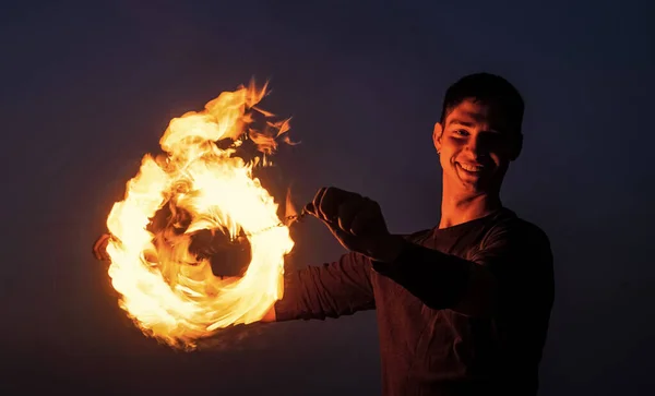 Mixing the danger and beauty. Fire performer at night. Happy poi performer. Burning poi twirling. Flaming circle. Holiday celebration. Outdoor festival. Bring the happiness with fire