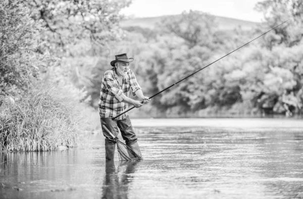 summer weekend. Big game fishing. man fly fishing. man catching fish. hobby and sport activity. pothunter. retired bearded fisher. Trout bait. fisherman with fishing rod. Men and fish are alike