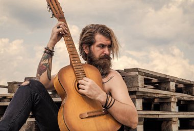 müzikal romantik balad. müzik teli enstrümanı. Olgun karizmatik erkek gitarist. Sakallı ve bıyıklı adam gitar çalıyor. Kareli gömlekli sakallı adam şarkı söylüyor. Müzisyen